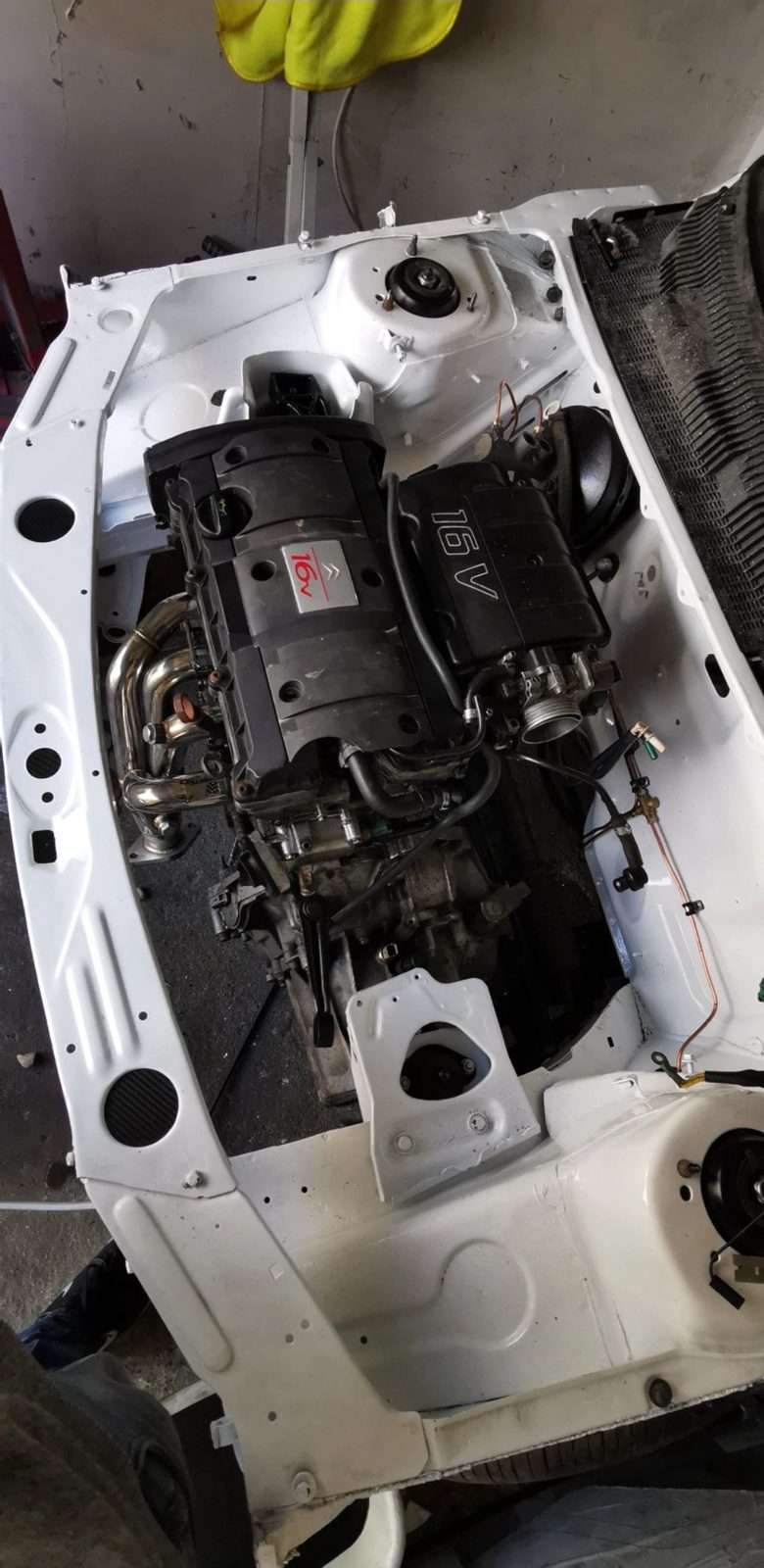 Engine bay of a white vehicle stripped for mechanical work