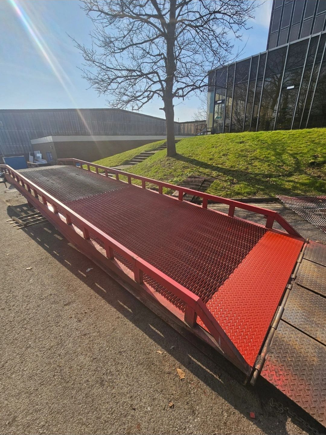 Red mobile loading ramp on site beside a factory