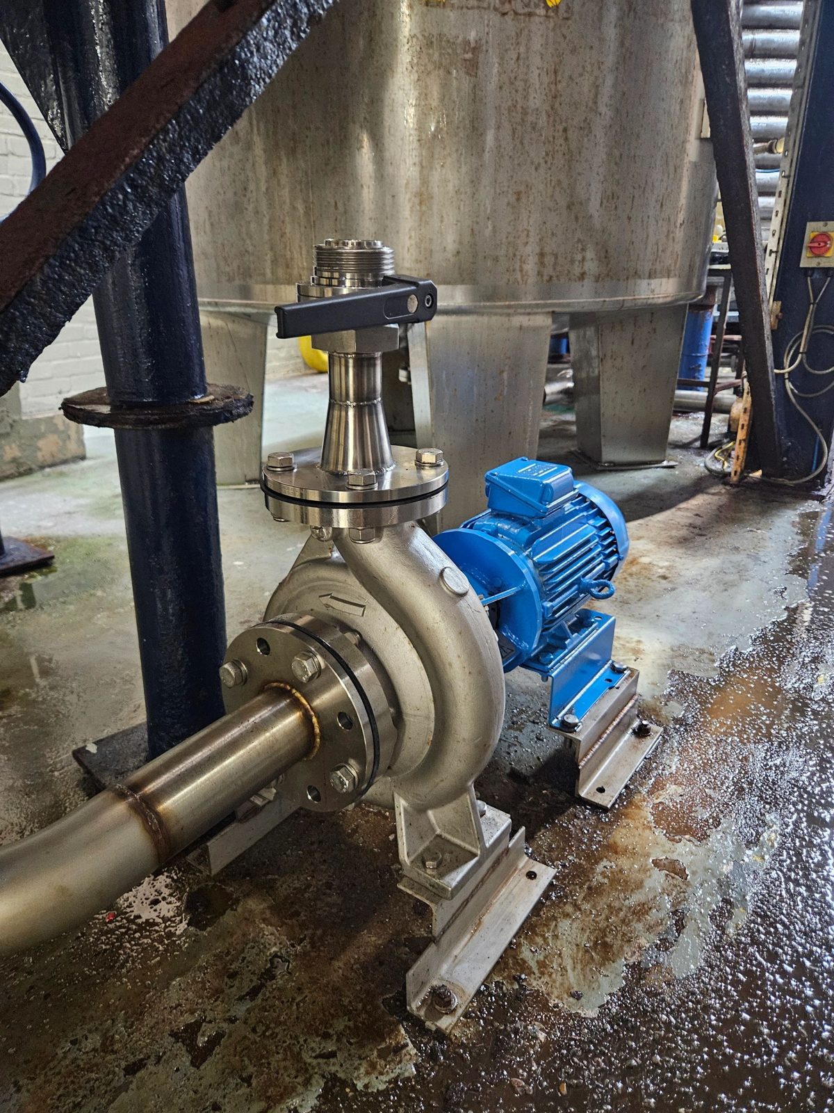 Stainless pump with blue motor installed beneath a steel tank