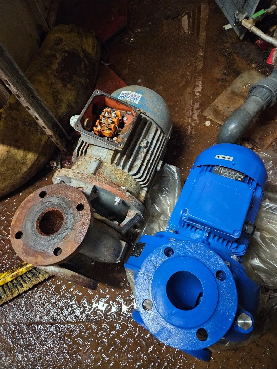 Old and new blue pump motors side by side on a chequer-plate floor