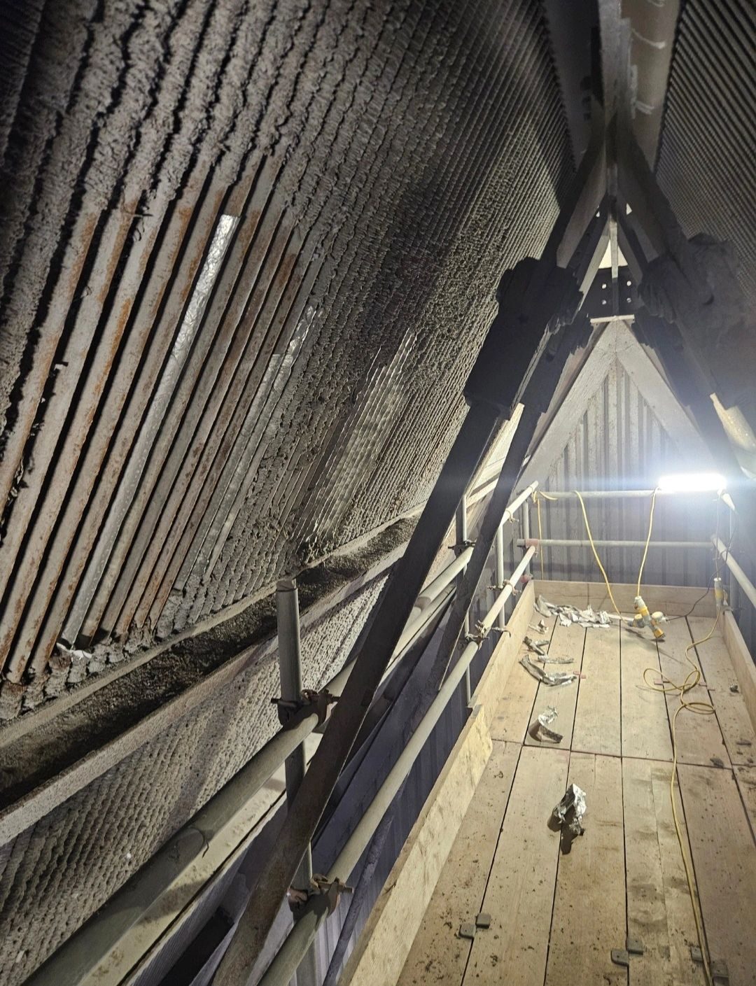 View inside an attic with wooden beams and lighting.
