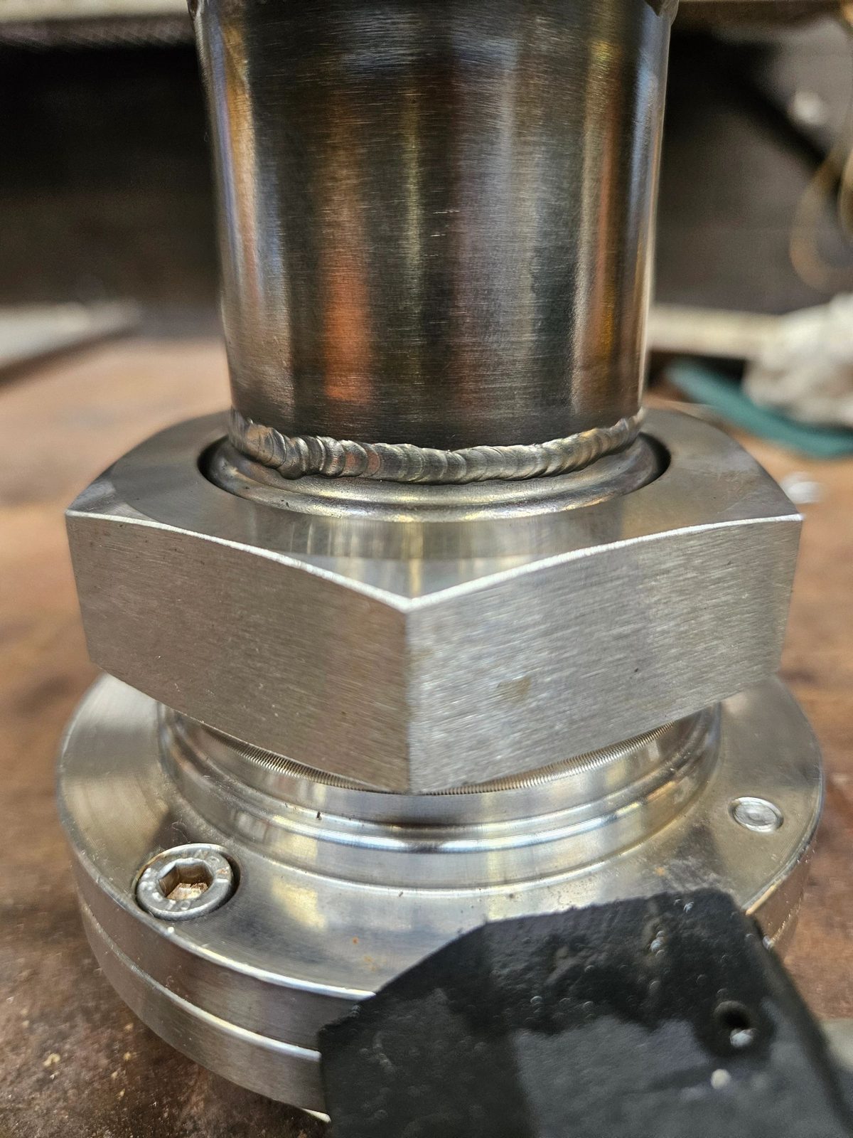 Close-up of a metal pipe with welded joint and hex nut.